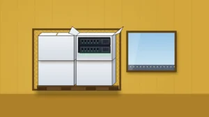 Stacked plain white cartons on a pallet inside a wire-mesh cage in a mustard-yellow warehouse. The top-right carton is open and shows two black rack servers with green indicator lights. A window at right looks onto an empty airport apron with a row of runway lights.